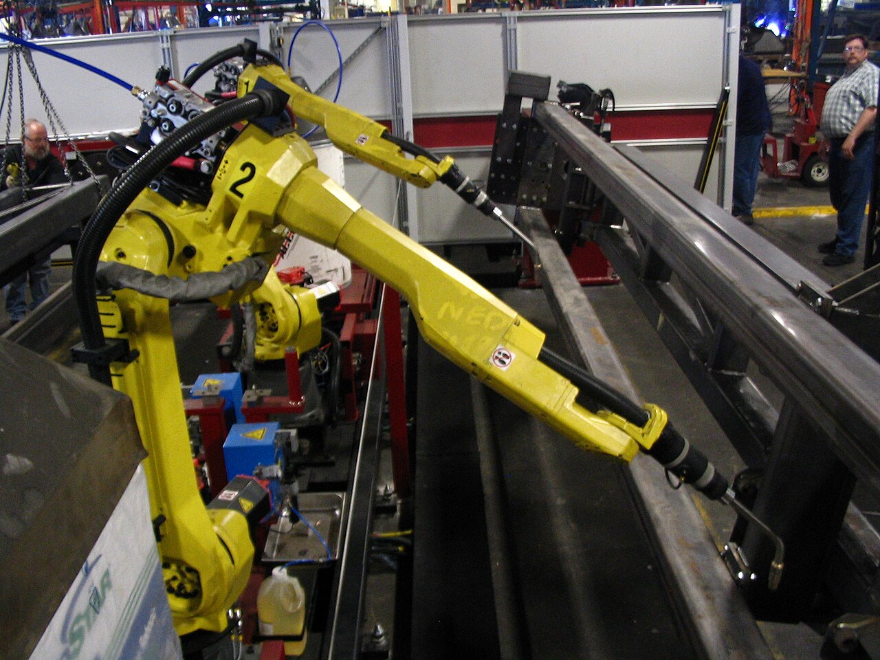 两台 FANUC 6 轴焊接机器人在工厂中作业